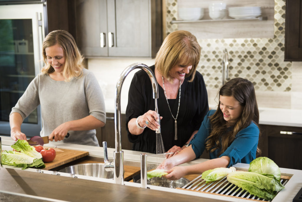 mother, daughter and granddaughter wash food in sink