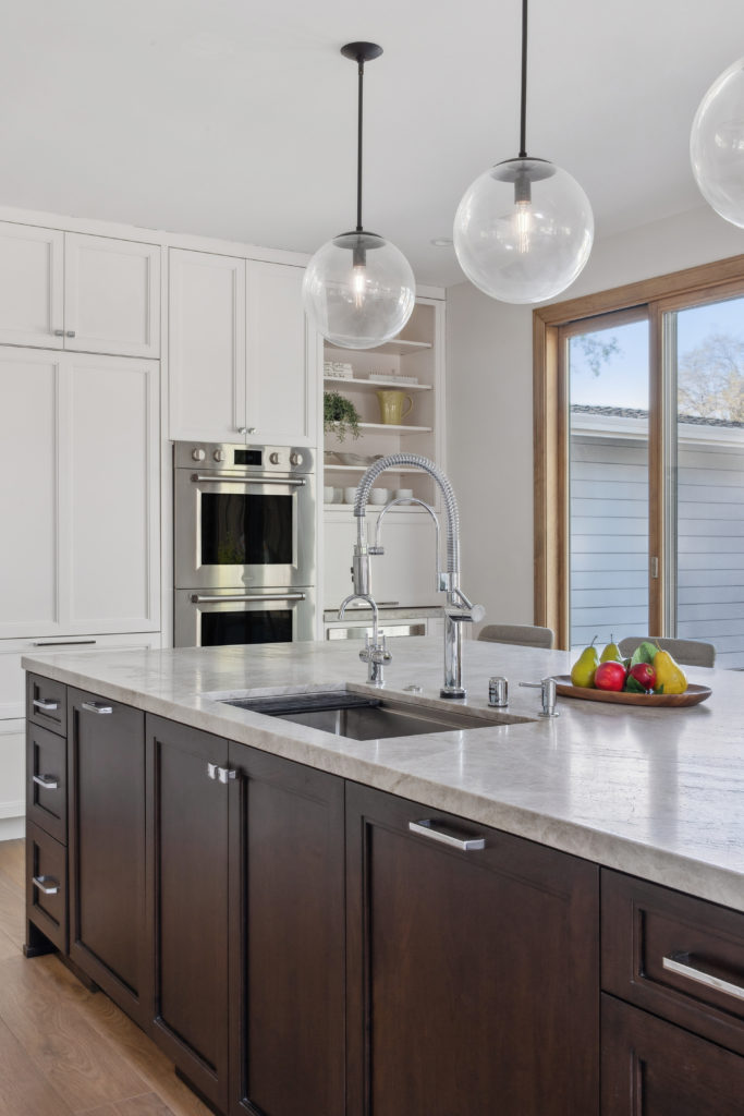 Dark wood cabinets for the island contrast with white kitchen cabinetry